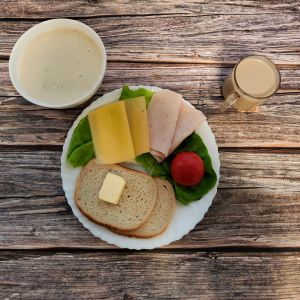 Zdjęcie przedstawia Dietę podstawową: Kawa zbożowa z mlekiem Owsianka z jabłkami Chleb mieszany pszenno-żytni Masło extra Szynka tostowa- drobiowa, średnio rozdrob. Ser ż&oacute;łty Pomidor Sałata zielona